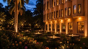 A hotel with outdoor seating, palm trees, and a well-lit facade. - Oriental Palace Resorts (Udaipur)