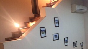 Una escalera con barandilla, un aire acondicionado instalado en la pared y varias fotografías enmarcadas.