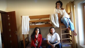 Habitación con literas, una escalera de madera, una puerta y una toalla colgada en la pared.