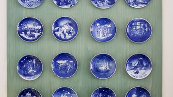 A collection of blue and white ceramic plates with various historical and cultural scenes, arranged in a grid on a green background.