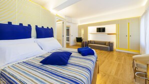 A modern hotel room with a large bed, a sofa, and a TV.