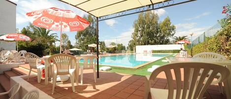 Een buitenzwembad, ligstoelen bij het zwembad