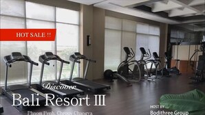 Une salle de sport équipée de tapis de course et de vélos d’appartement, dotée de grandes fenêtres et d’un design moderne.