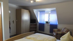 A bedroom with a bed, a wardrobe, a television, and a window with curtains. - Pension-Neuenrade (Neuenrade)