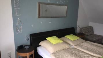 A bedroom with a bed, a nightstand, a chair, and a wall-mounted mirror.