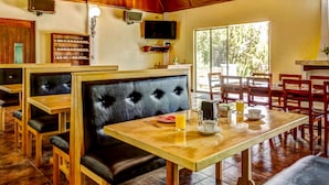Un restaurante con cabinas de madera, un televisor en la pared y una disposición para desayuno en una mesa.