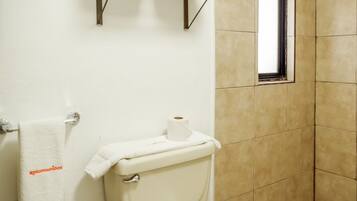 A bathroom with a toilet, a towel rack, and a window.