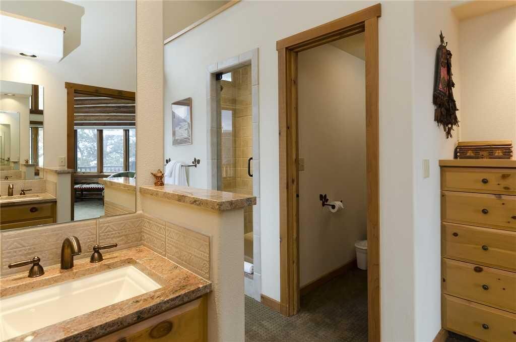 Un baño con un espejo grande, un lavabo y un armario de madera.