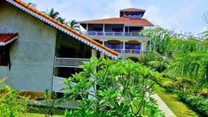 A two-story building with a red-tiled roof and a balcony. - Thambili cabanas (Hikkaduwa)