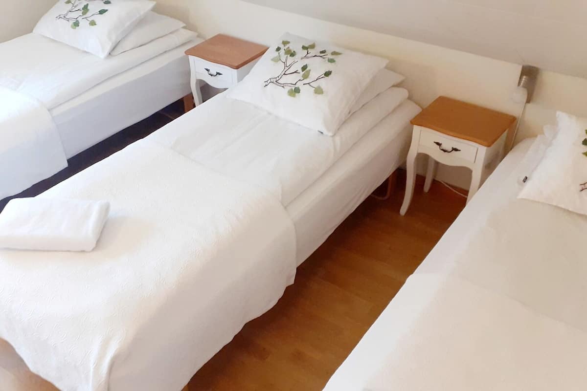 A hotel room with two single beds, each with a wooden nightstand and a white pillow with a tree design.