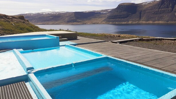 A swimming pool with a view of a lake and mountains in the background.