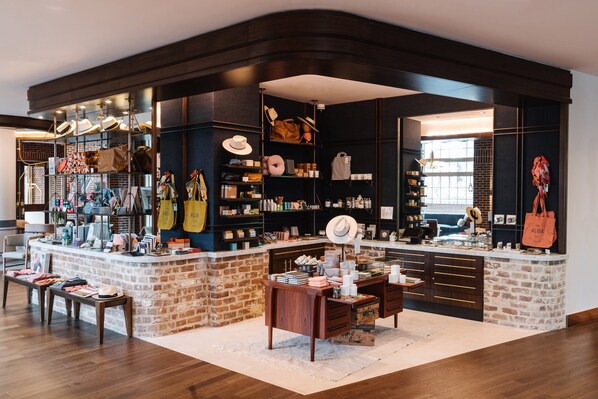A boutique store with a brick counter, shelves of hats and bags, and a cozy seating area.