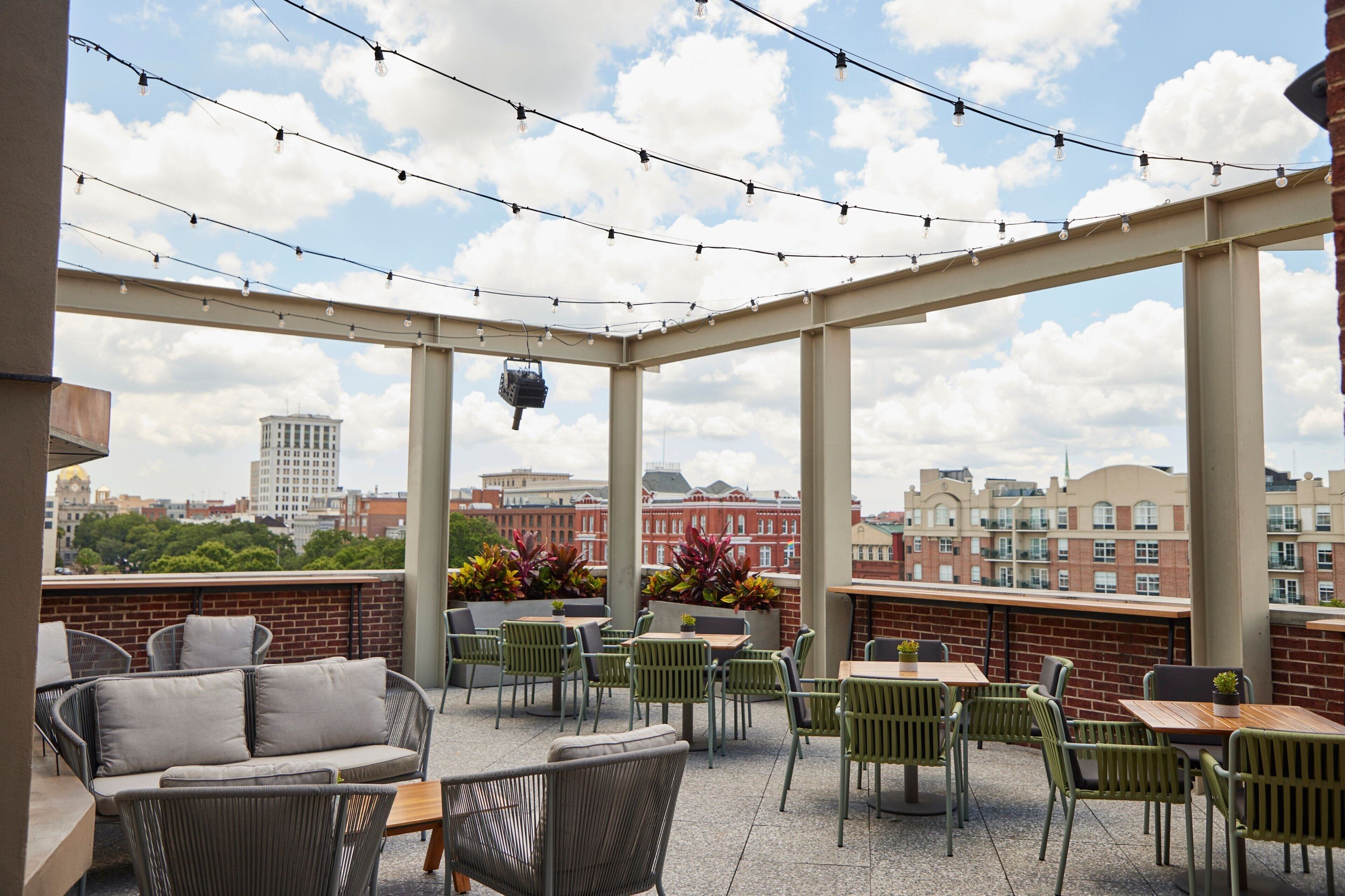 A rooftop patio with outdoor seating, string lights, and a city view.
