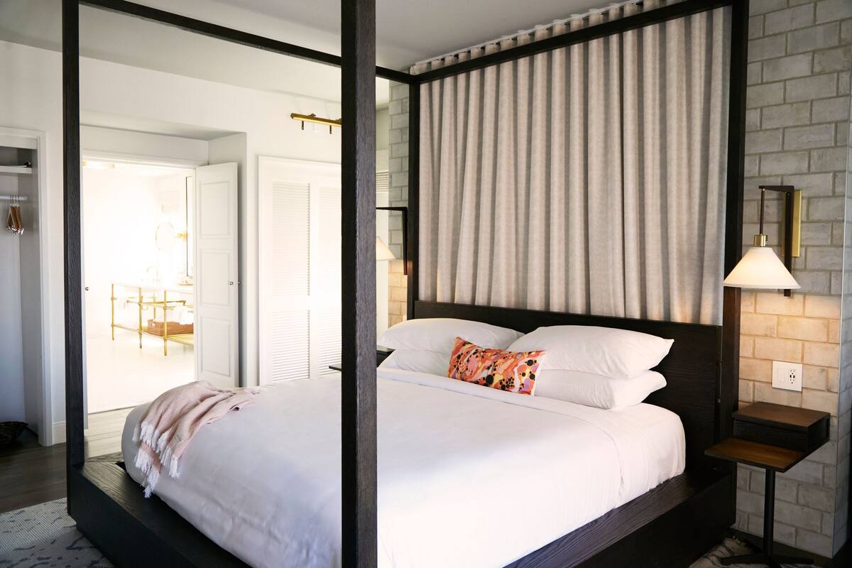 Ein modernes Hotelzimmer mit einem großen Bett, einem Nachttisch und Blick ins Freie.