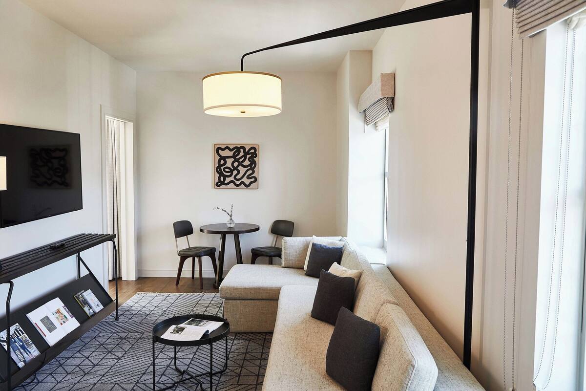 Ein modernes Wohnzimmer mit einer Couch, einem Couchtisch, einem Fernseher und einem Essbereich mit Stühlen und einem Tisch.