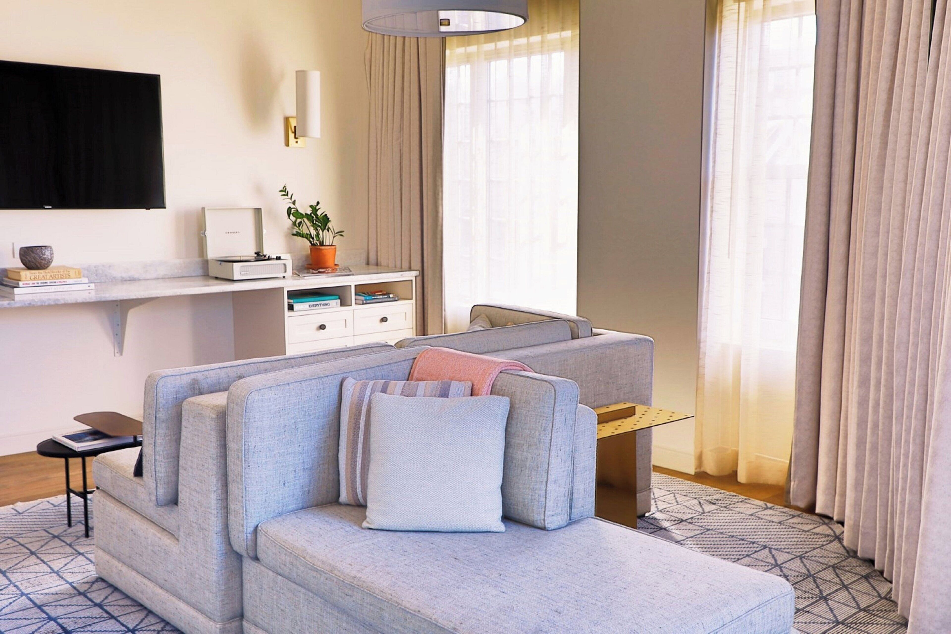 Una sala de estar moderna con un sofá gris, una mesa de centro y un televisor de pantalla plana montado en la pared.