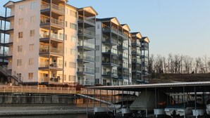 A multi-story residential building with balconies, a covered dock area, and boats.