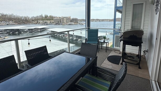 A balcony with a table and chairs, a ceiling fan, and a view of the water and buildings.