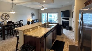 A modern kitchen with a central island, built-in appliances, and a dining area with dark wood furniture.