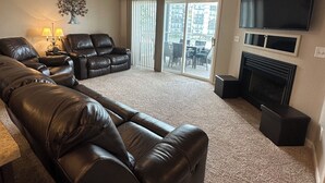A living room with a large sectional sofa, a flat-screen TV, and a fireplace.
