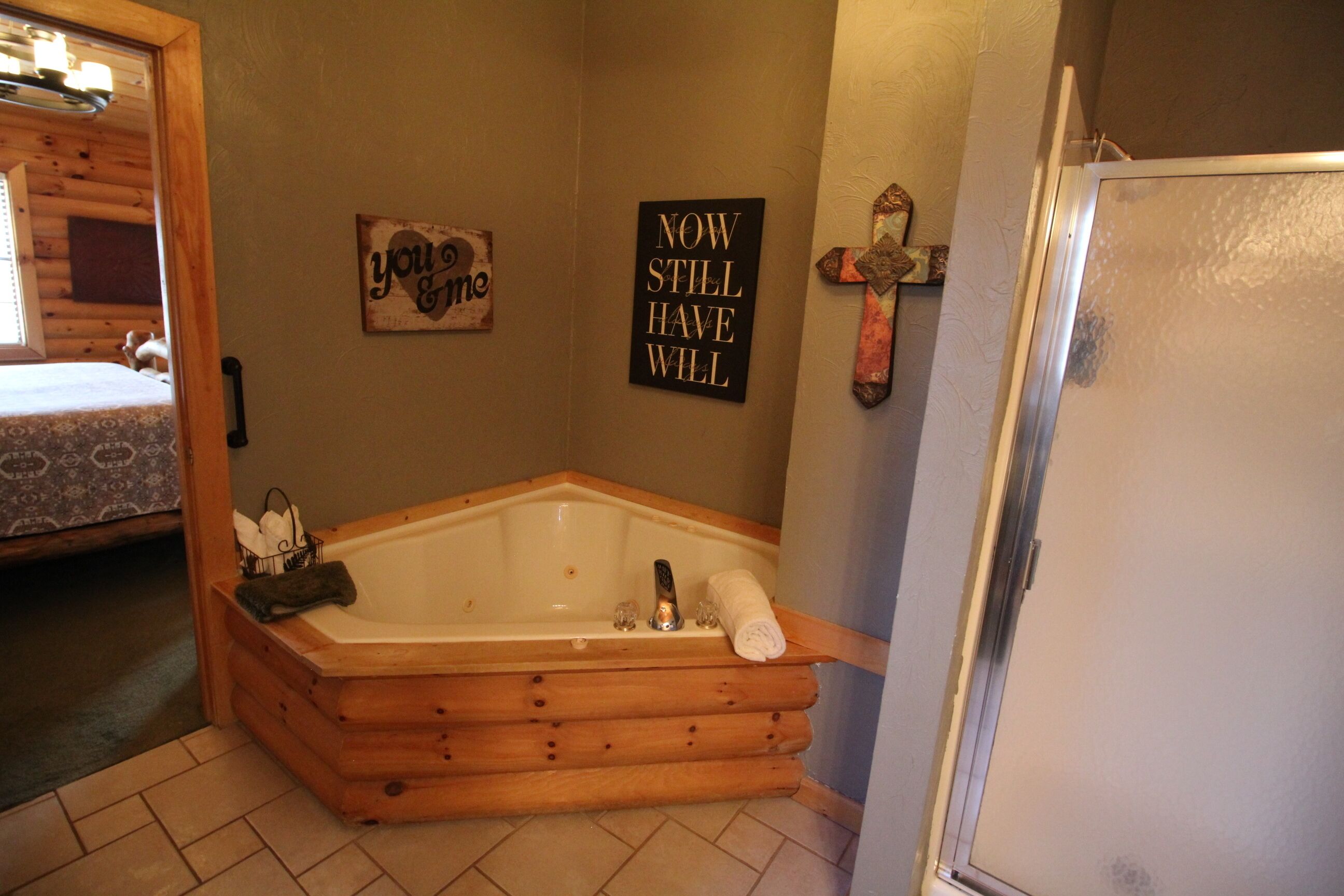 Una bañera de madera en un baño, con una toalla, un cartel en la pared y un refrigerador.