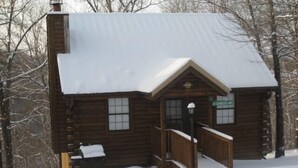 Une cabane en bois avec un toit enneigé et une véranda.