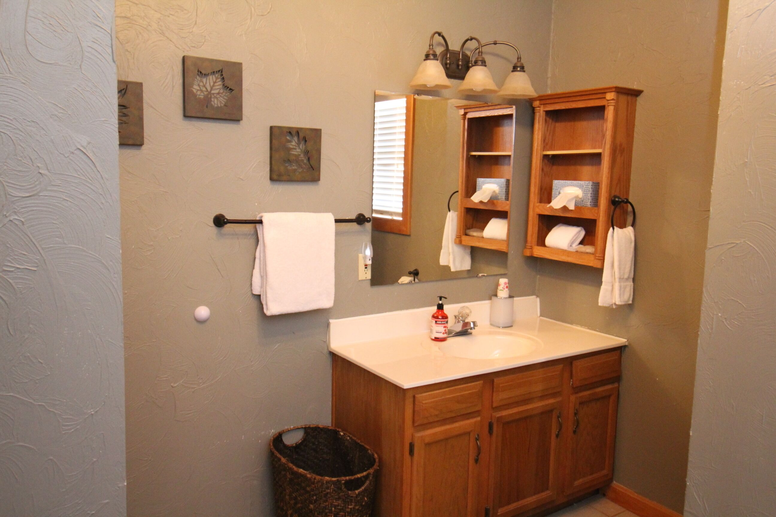 A bathroom with a wooden vanity, a sink, a mirror, and a towel rack.