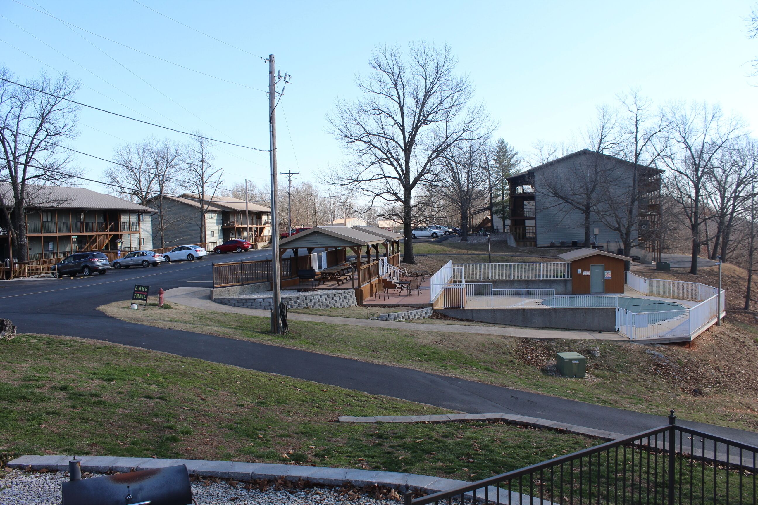 A building with a covered patio area, a small fenced playground, and a visible fire hydrant.