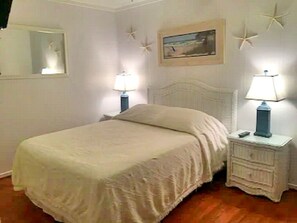 A bedroom with a bed, two bedside tables with lamps, a mirror, and starfish decorations on the wall.