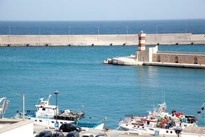 A harbor with boats docked, a lighthouse, and a concrete breakwater.