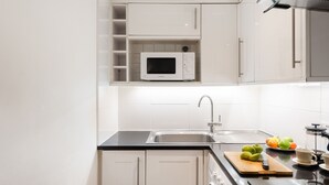 Eine moderne Küche mit weißen Schränken, einer Mikrowelle, einem Spülbecken und einem Schneidebrett mit Äpfeln.