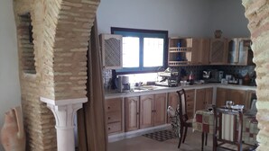 A kitchen with a brick archway, wooden cabinets, a coffee maker, and a dining area with chairs. - Luxury Home With Unique Gulf View Of Hammamet (Hammamet)