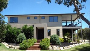 A two-story house with a front porch, a small deck, and a well-maintained lawn.