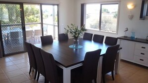 A dining area with a large table, six chairs, and a vase with flowers.