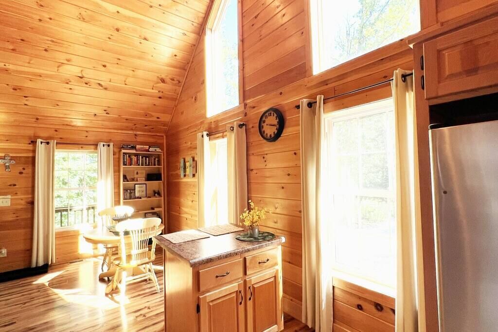 L’intérieur d’un chalet en bois comprend un coin cuisine, des murs en bois, une table à manger et une bibliothèque.