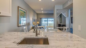 A modern kitchen with a marble countertop, stainless steel sink, and recessed ceiling lights. - Ocean View and only steps to the sand !! (Fenwick Island)