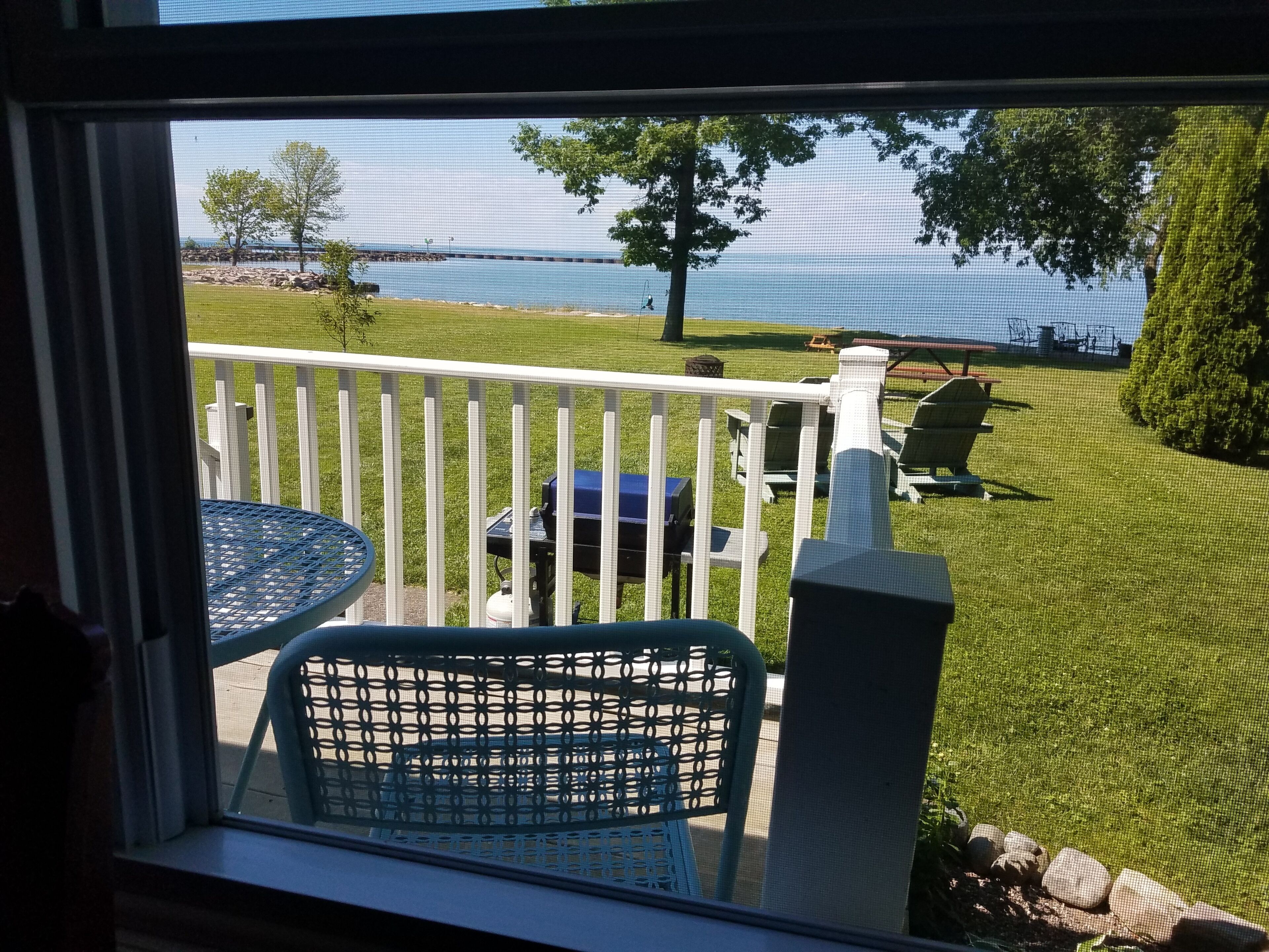 Un balcon avec vue sur un lac, une pelouse et des meubles d’extérieur.