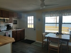 A kitchen with wooden cabinets, a white stove, and a dining area with a table and chairs.