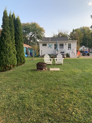 A house with a front porch, two white Adirondack chairs, a fire pit, and a welcome sign. - A park-like oasis (Kent)