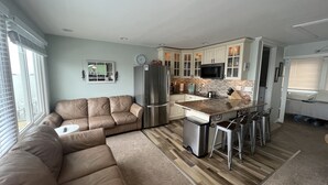 A modern kitchen with white cabinets, a stainless steel refrigerator, and a central island with bar stools. - Middle of Dewey ,On the Bay, Close to the Beach  (Dewey Beach)