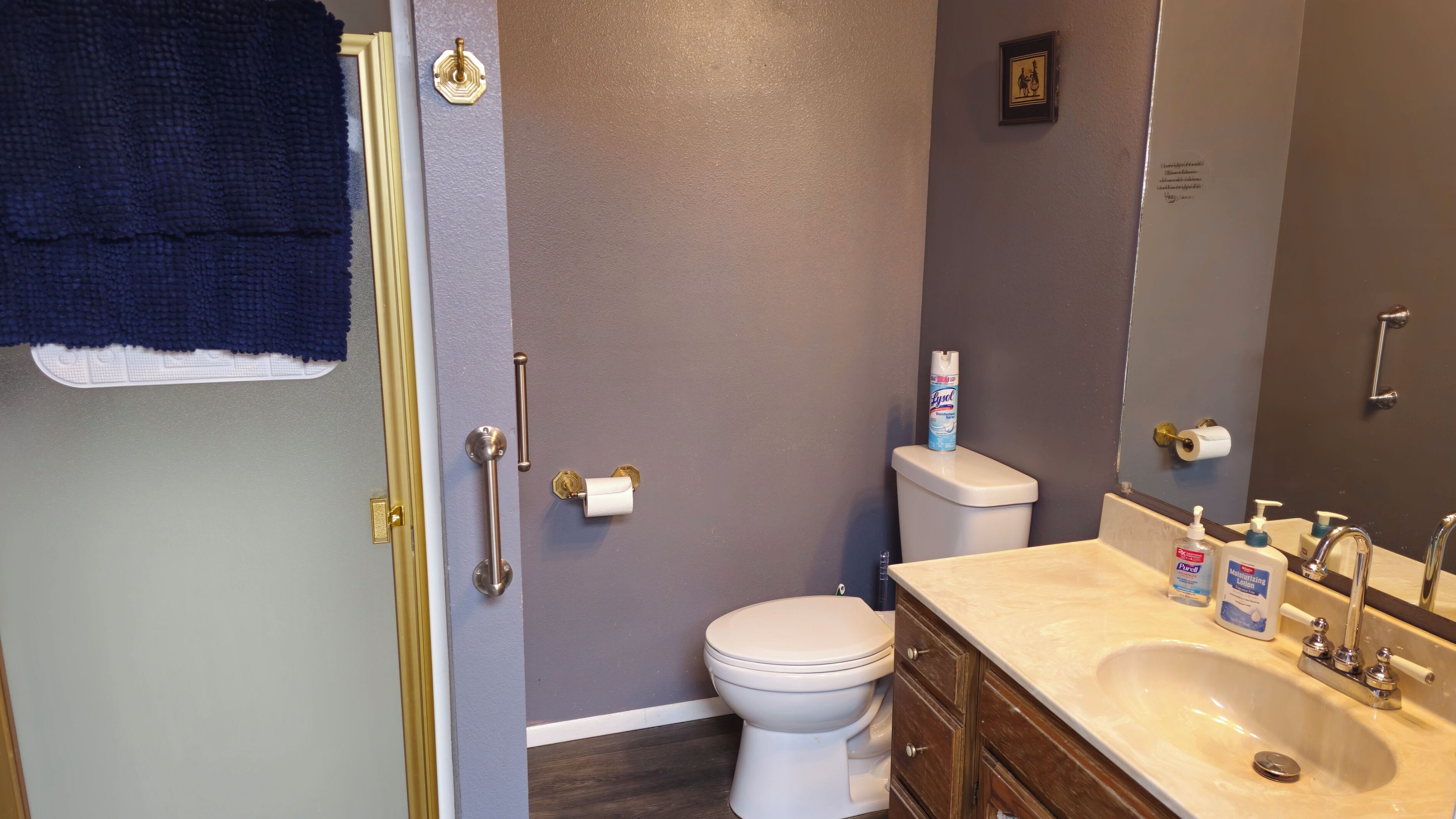 A bathroom with a toilet, sink, and a towel hanging on the door.