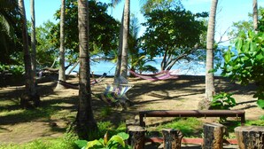 Escena de playa con palmeras, una hamaca y un banco.