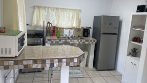 Una cocina compacta equipada con microondas, estufa, fregadero y refrigerador.