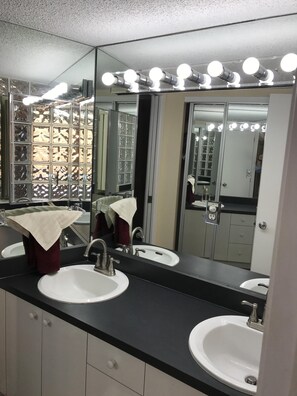 Une salle de bain avec deux lavabos, un grand miroir et un meuble-lavabo doté d’un porte-serviettes.