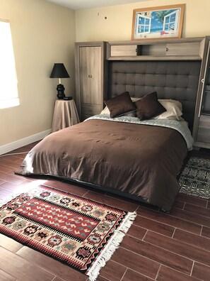 Une chambre à coucher avec un lit, une table de chevet, une lampe, une armoire et un tapis.