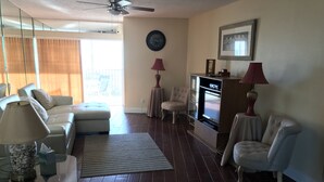 A living room with a sofa, armchair, and a TV stand with a TV. - ON the Beach, 2nd Floor, Elevator, Heated swimming pool and Spa, Freshly painted (Longboat Key)