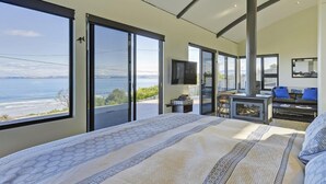 A spacious bedroom with a large bed, a television, and a view of the sea. - Park Beach Retreat - Ideal for couples (Dodges Ferry)