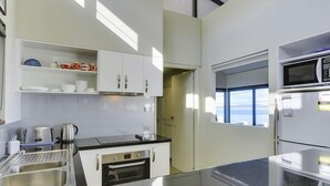 A modern kitchen with white cabinets, a stainless steel sink, a built-in oven, and a microwave. - Park Beach Retreat - Ideal for couples (Dodges Ferry)