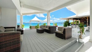 A covered outdoor seating area with wicker furniture, potted plants, and a view of the sea. - BEST VALUE! New reno, Beach 10' from door, water 50' away WE MOVED ID 5216594 !! (Red Hook)