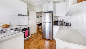 Una cocina moderna con armarios blancos, un refrigerador de acero inoxidable, un microondas y una tostadora.